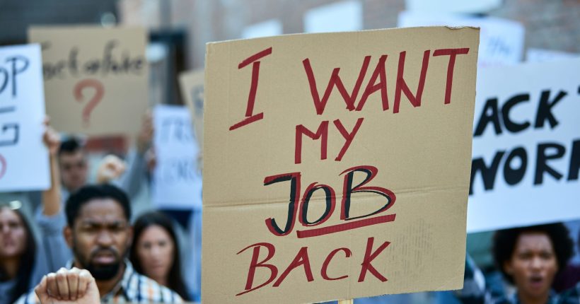 Crowd of unemployed people protesting against loosing their jobs due to coronavirus pandemic. Focus in on banner with I want my job back inscription.